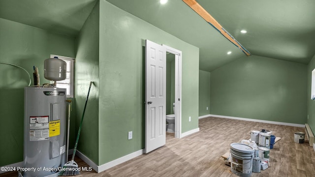 interior space with light hardwood / wood-style floors, lofted ceiling, and water heater