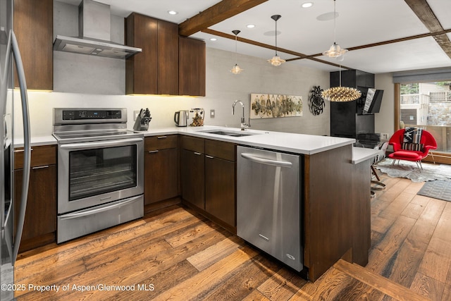 610 S W End St Unit K102, Aspen, CO 81611 - kitchen with appliances with stainless steel finishes, wall chimney exhaust hood, a sink, a peninsula, and dark wood-style floors