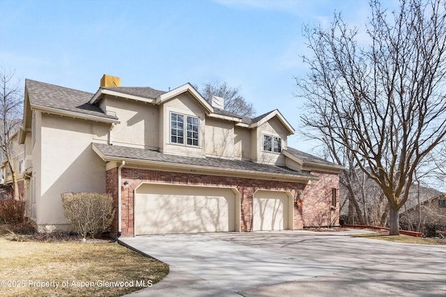 view of front of home with brick siding, concrete driveway, stucco siding, a chimney, and a garage