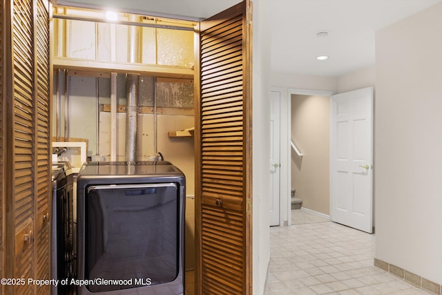 clothes washing area featuring baseboards, laundry area, and washer and clothes dryer