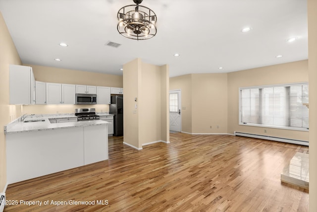 kitchen with visible vents, a baseboard radiator, stainless steel appliances, white cabinets, and open floor plan