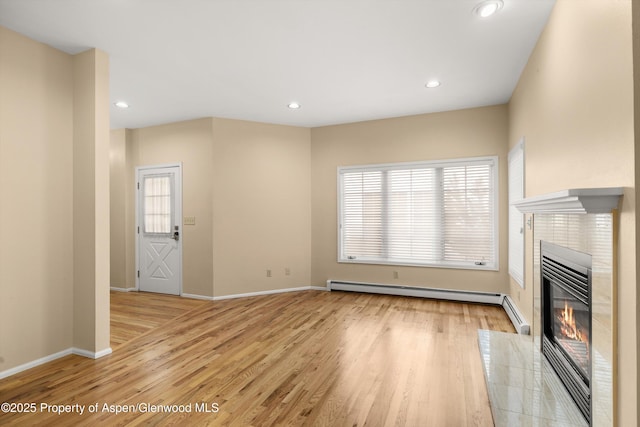 unfurnished living room with a healthy amount of sunlight, light wood-style flooring, and a tiled fireplace