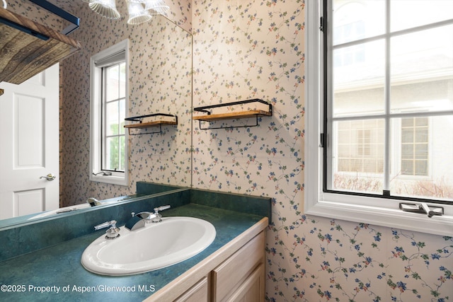 bathroom with wallpapered walls and vanity