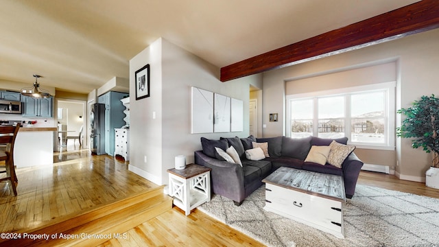 living area with baseboards, beam ceiling, and light wood-style floors