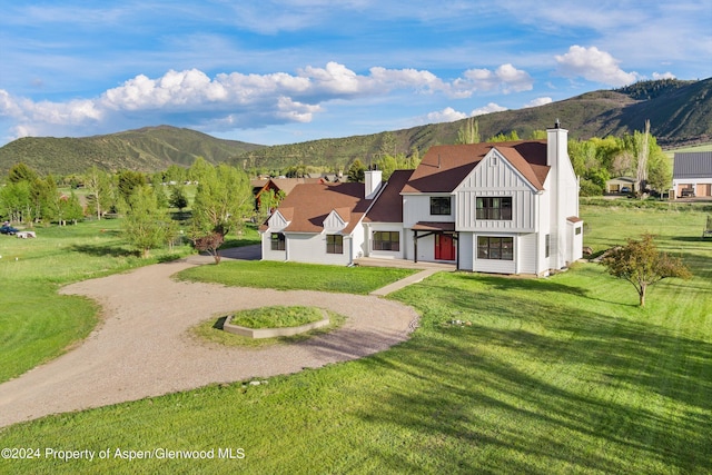 view of front of house featuring board and batten siding, a mountain view, a chimney, and dirt driveway