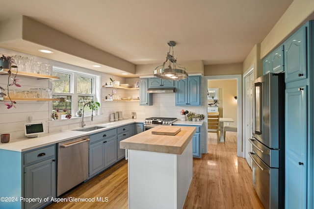 kitchen with premium appliances, butcher block counters, a kitchen island, a sink, and open shelves