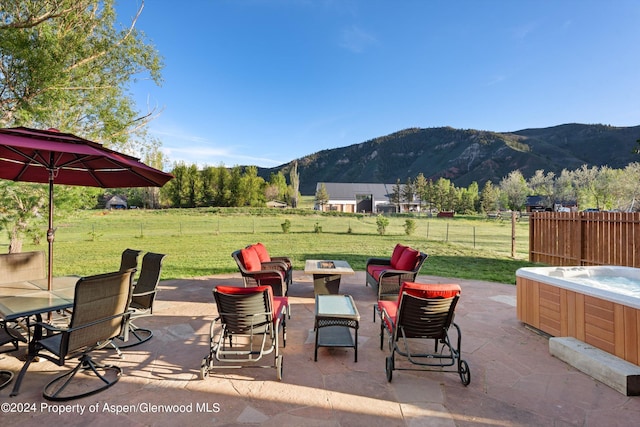 view of patio with fence, a mountain view, and a hot tub