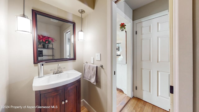 half bath featuring baseboards, wood finished floors, and vanity