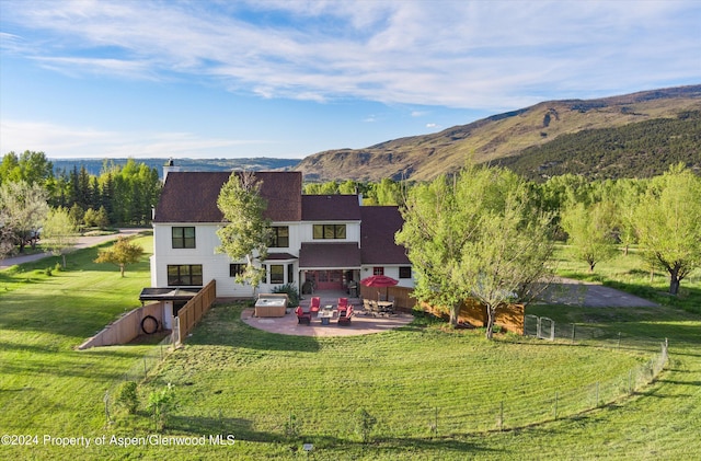 back of property featuring a rural view, fence private yard, a mountain view, a lawn, and a patio area