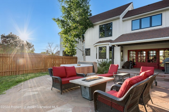 view of patio / terrace featuring french doors, an outdoor living space with a fire pit, fence, and a hot tub