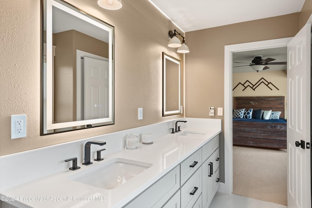 full bath with a sink, double vanity, ceiling fan, and ensuite bath