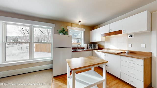 kitchen featuring freestanding refrigerator, a sink, light countertops, white cabinetry, and backsplash