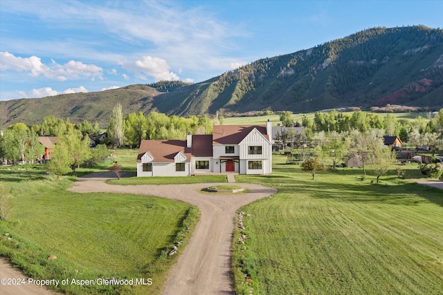 view of front of home featuring a front yard, a mountain view, and dirt driveway