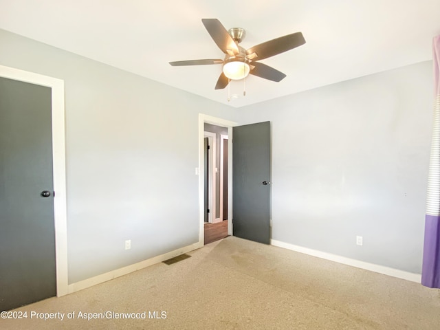 carpeted spare room with ceiling fan