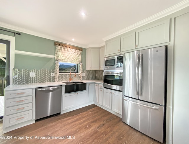 kitchen with decorative backsplash, stainless steel appliances, crown molding, sink, and dark hardwood / wood-style floors