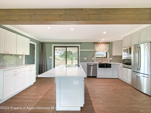 kitchen with appliances with stainless steel finishes, backsplash, a kitchen island, sink, and white cabinetry