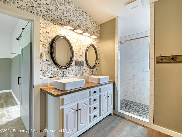 bathroom with tiled shower, vanity, and hardwood / wood-style flooring