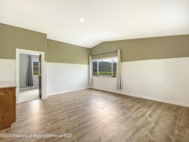 empty room with light hardwood / wood-style floors and lofted ceiling