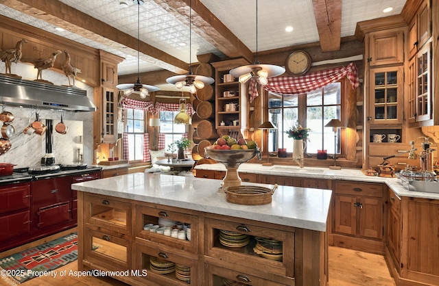 kitchen featuring beamed ceiling, a center island, decorative light fixtures, and ventilation hood