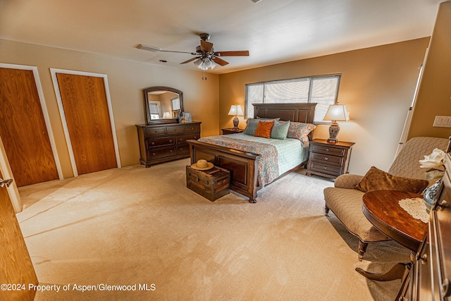 carpeted bedroom featuring a ceiling fan and multiple closets