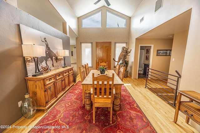 dining space with light wood-type flooring and high vaulted ceiling