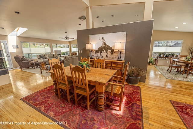 dining area featuring hardwood / wood-style floors, a ceiling fan, a skylight, recessed lighting, and lofted ceiling