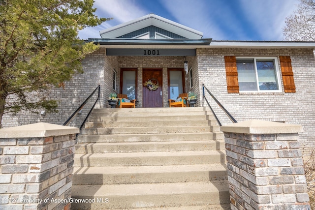 entrance to property featuring brick siding and covered porch