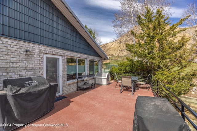 view of patio / terrace with outdoor dining area, a grill, and a mountain view
