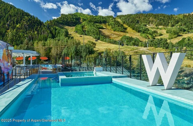 550 S Spring St Unit F8-10, Aspen, CO 81611 - view of pool featuring a wooded view and a pool with connected hot tub