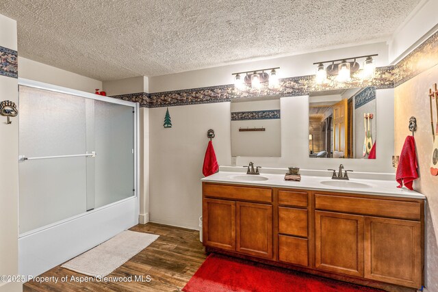 3 Hazel Lake Dr, Cimarron, CO 81220 - bathroom featuring wood finished floors, double vanity, shower / bath combination with glass door, and a textured ceiling