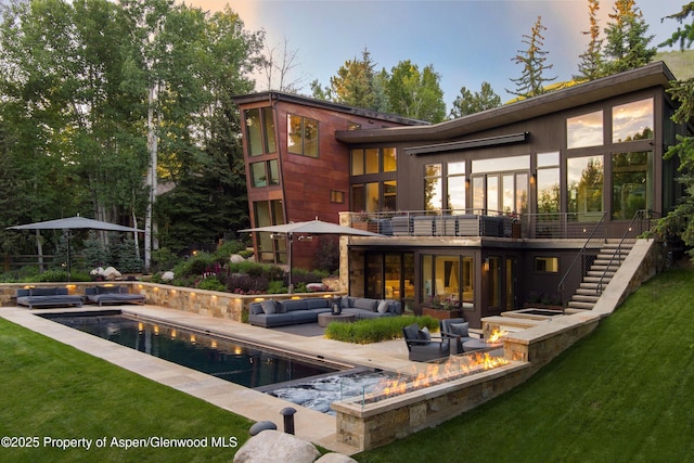 62 Bennett Ct, Aspen, CO 81611 - back of house at dusk featuring an outdoor living space with a fire pit, stairway, a patio area, an outdoor pool, and a lawn