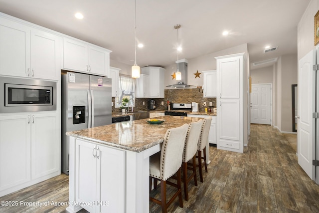 2432 Pioneer Way, Rifle, CO 81650 - kitchen featuring wall chimney exhaust hood, stainless steel appliances, white cabinets, dark wood-style flooring, and a kitchen island