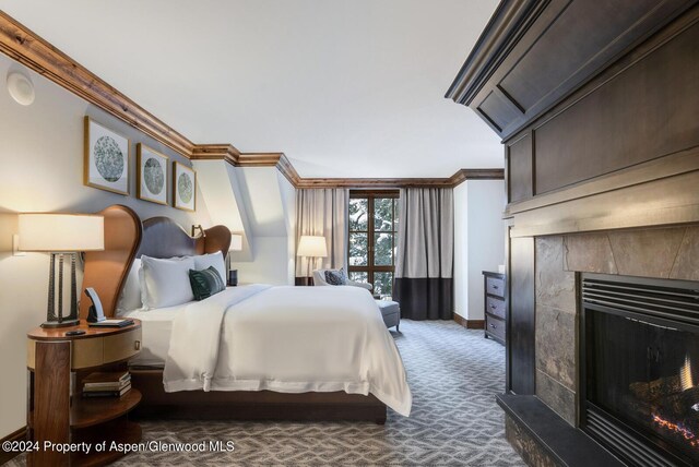 carpeted bedroom with a tiled fireplace and crown molding