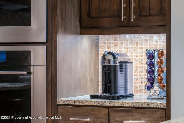 details with light stone countertops, dark brown cabinets, and stainless steel oven