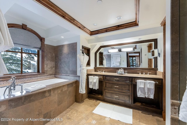 bathroom with a raised ceiling, crown molding, vanity, and a relaxing tiled tub