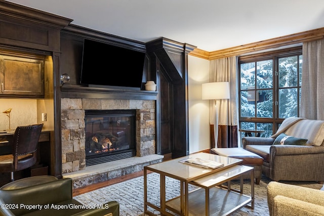 living room with a stone fireplace and crown molding