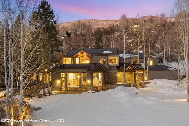 view of front of house with stone siding, a standing seam roof, metal roof, and a mountain view