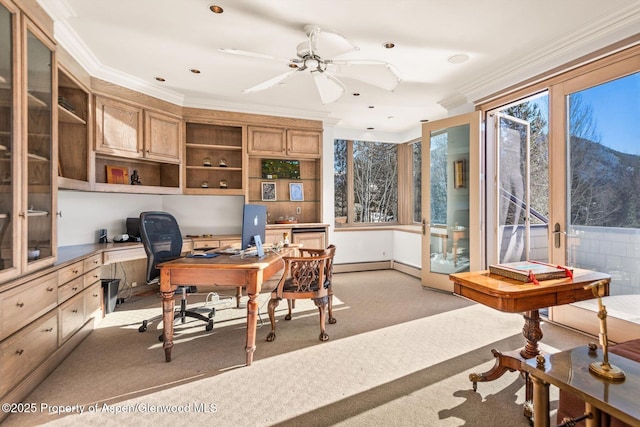 home office featuring ornamental molding, built in desk, a healthy amount of sunlight, and light colored carpet