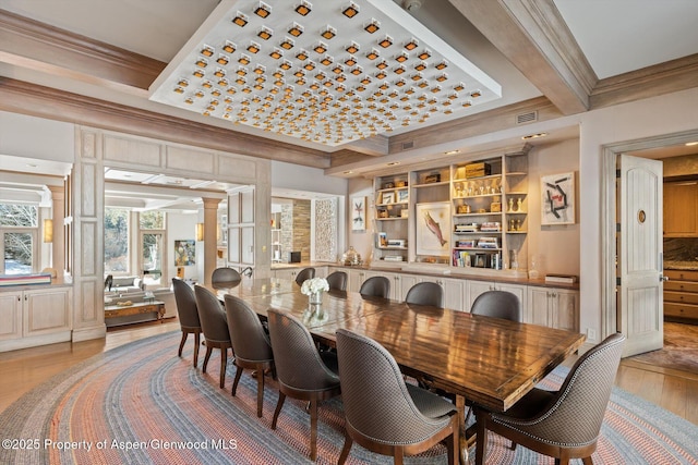 dining area with ornamental molding, visible vents, decorative columns, and light wood finished floors