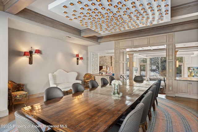 dining area with crown molding, decorative columns, wood finished floors, beamed ceiling, and baseboards