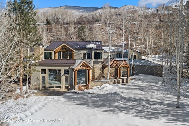 chalet / cabin with metal roof, a standing seam roof, stone siding, and a mountain view