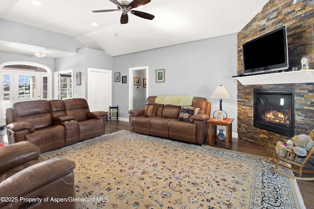 living room featuring vaulted ceiling, ceiling fan, a fireplace, and hardwood / wood-style flooring