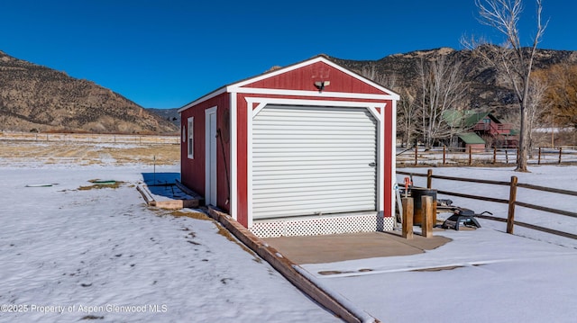 snow covered structure with a mountain view and a garage