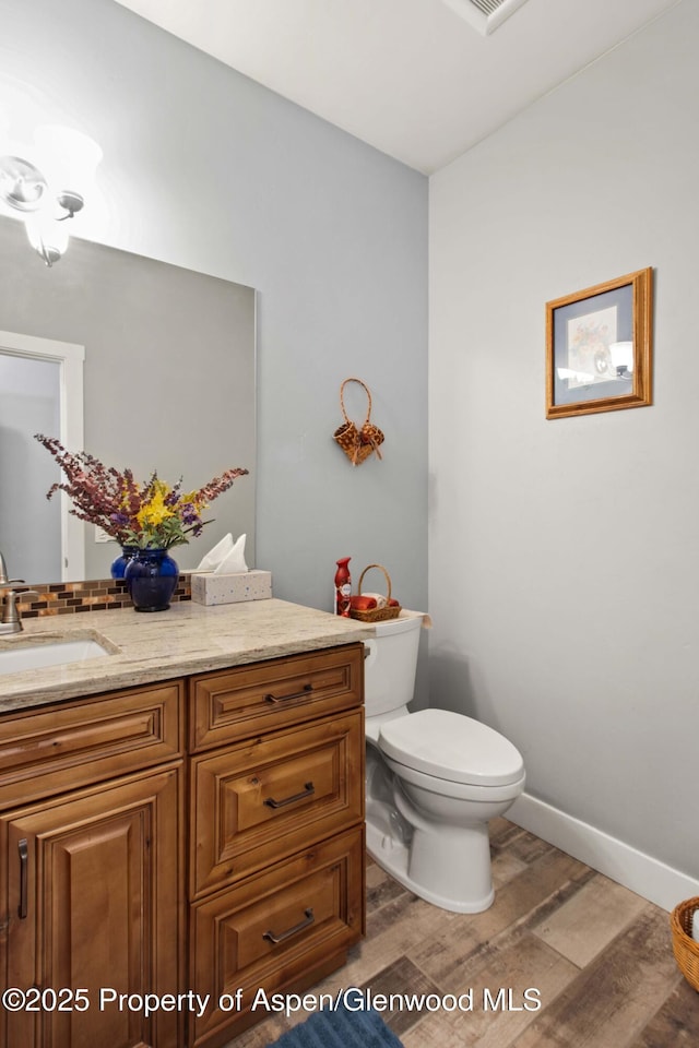 bathroom with toilet, wood-type flooring, and vanity