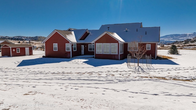 snow covered house with a mountain view and a storage unit