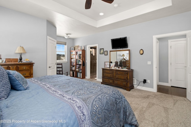 carpeted bedroom featuring ceiling fan and a raised ceiling