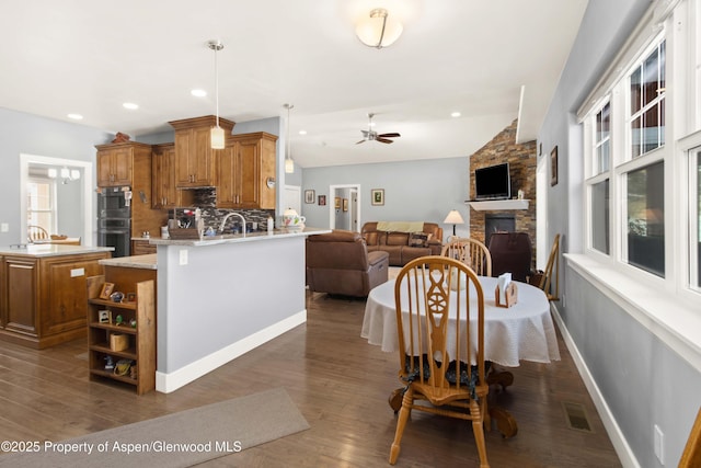 dining room featuring ceiling fan, dark wood-type flooring, a fireplace, and lofted ceiling