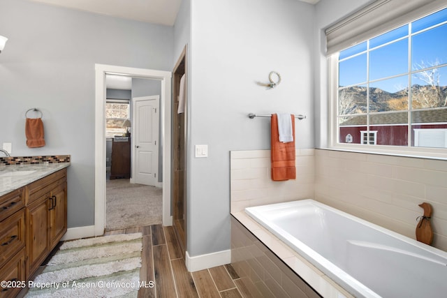 bathroom with a mountain view, tiled tub, and vanity