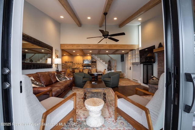 living room with a high ceiling, ceiling fan, and beam ceiling