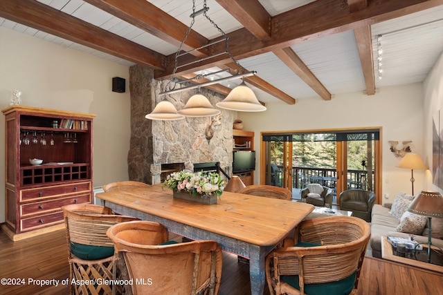 dining space featuring french doors, dark hardwood / wood-style flooring, beam ceiling, wooden ceiling, and a stone fireplace